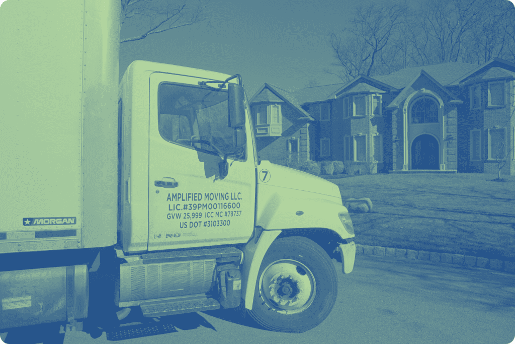 Lateral view of an Amplified moving labeled truck parked in front a large house