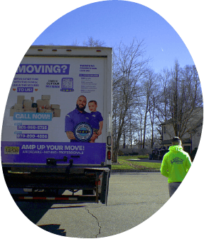 Back view of an amplified moving labeled truck and a man with a yellow amplified moving walking beside it