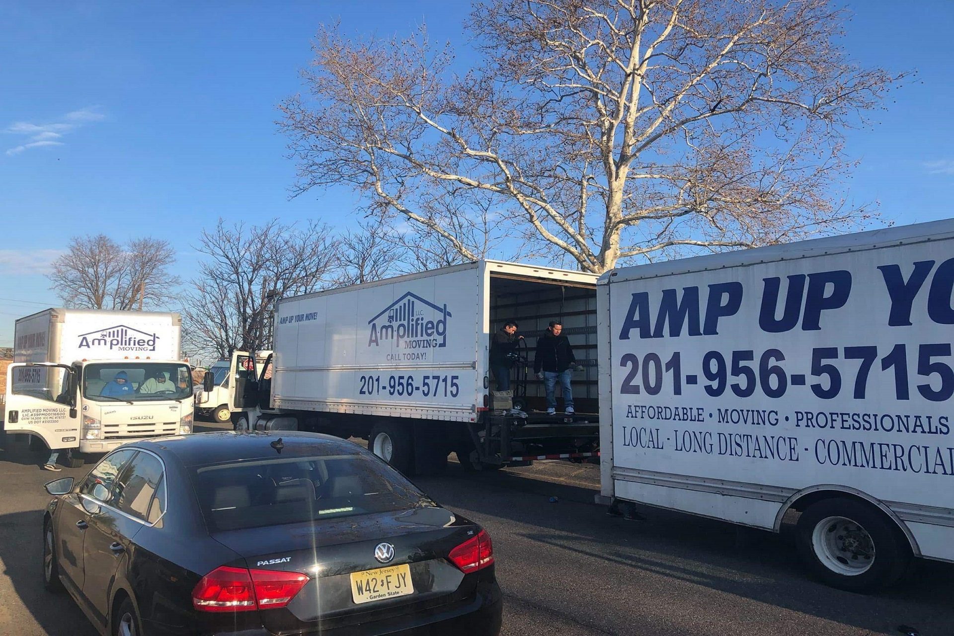 Three amplified moving trucks parked in a driveway.