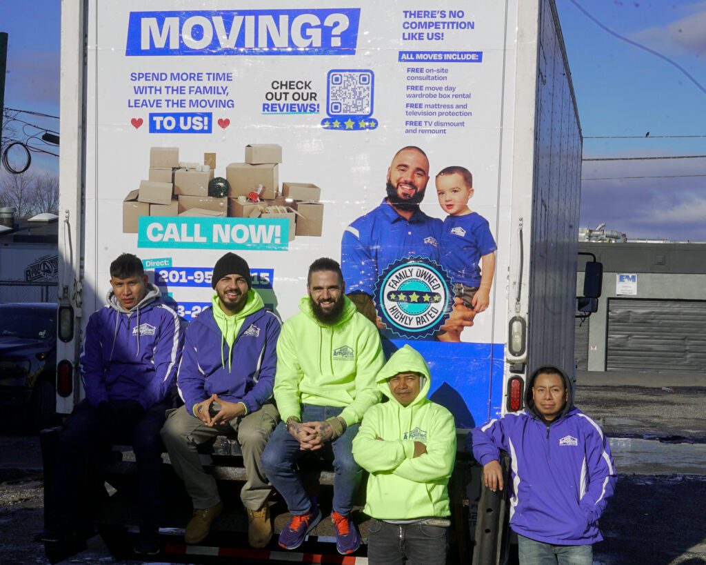 Five team members posing at the back of an amplified moving branded truck