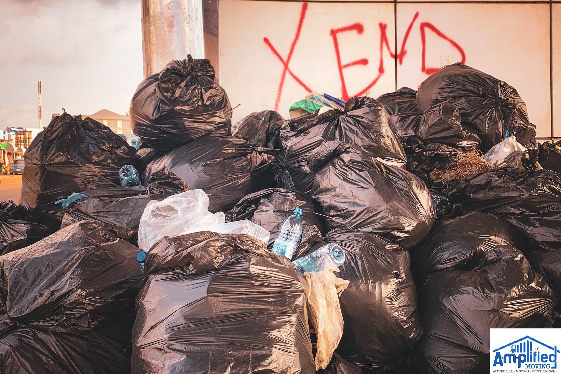 Trash bags full and piled near a wall.