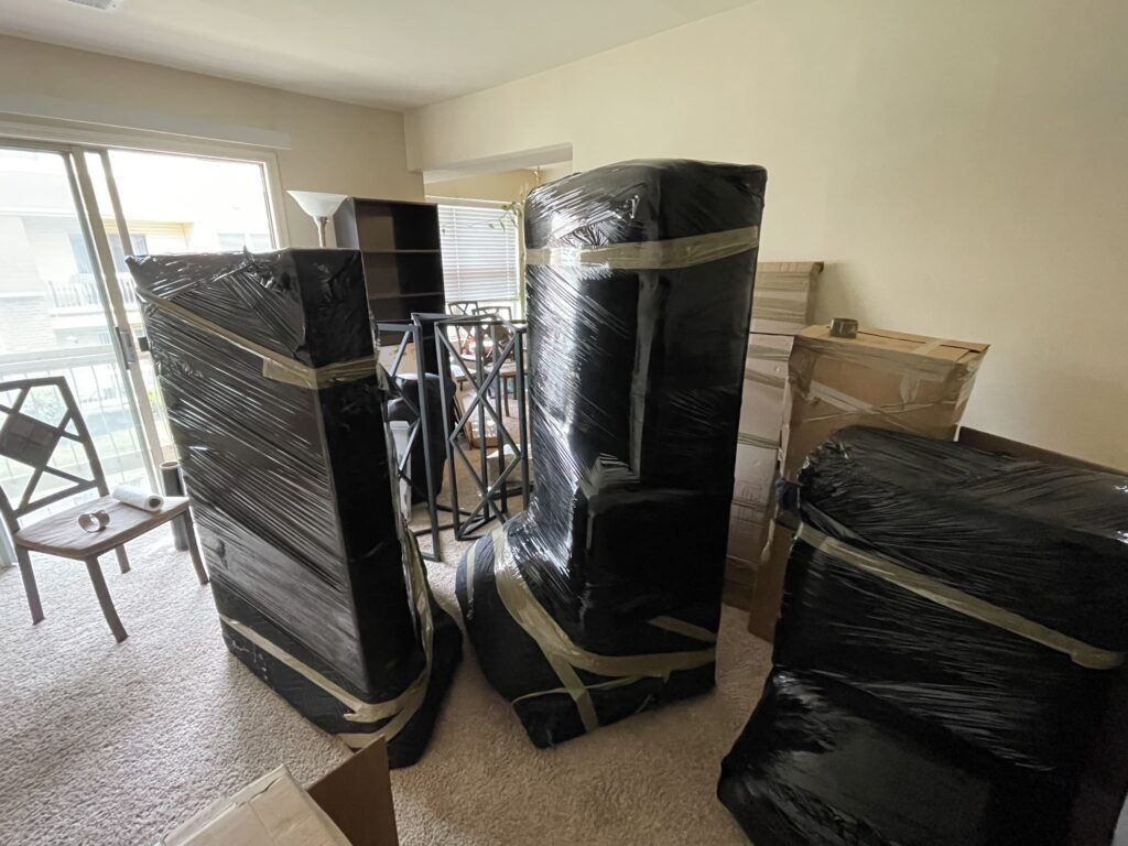 Big items carefully covered with plastic and cardboard ready to be moved form a living room.