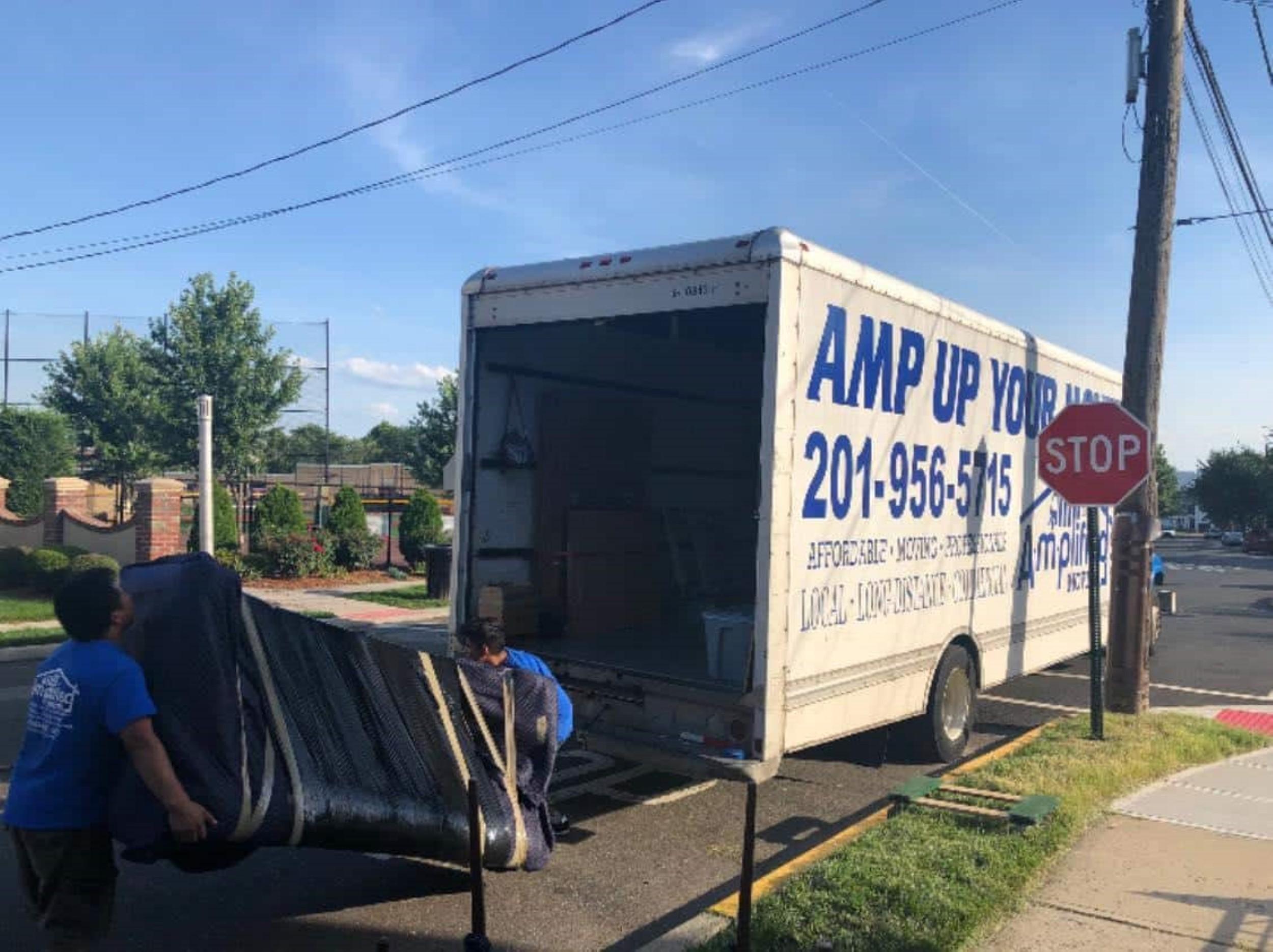 Two men carefully loading a couch in to a truck container.