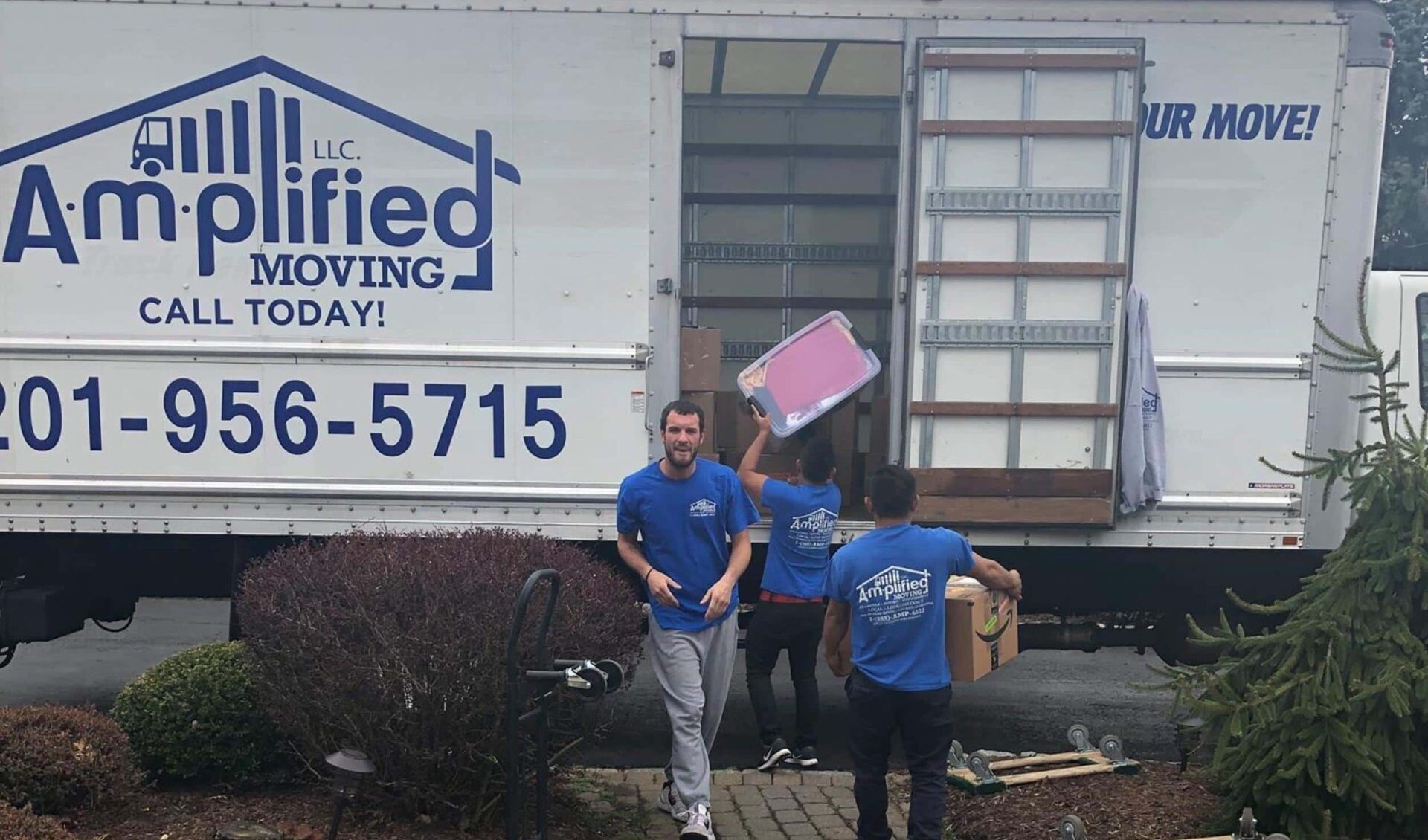 Movers diligently loading a truck with amplified moving logo.