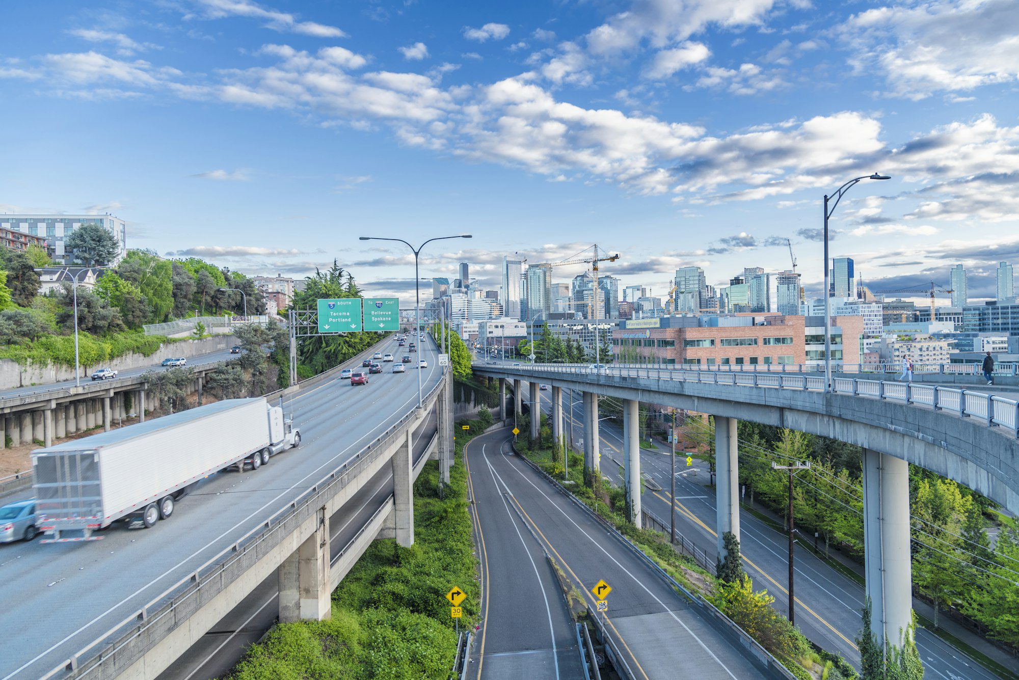 A semi truck cruising through a highway approaching a big city.