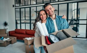 Young couple with a cardboard box ready to move.