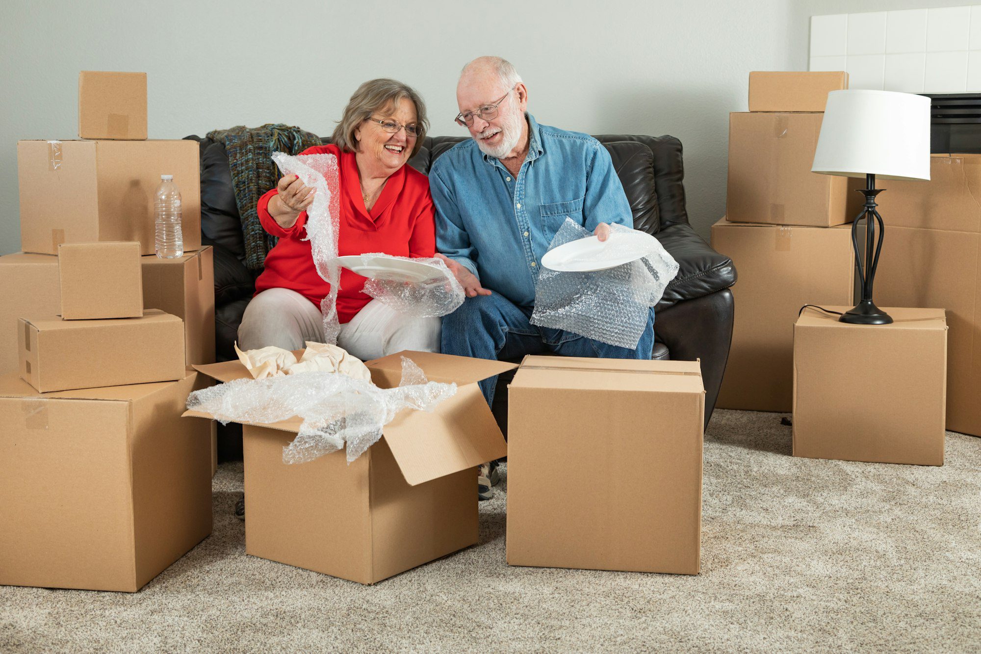 Senior Adult Couple Packing Moving Boxes in a living room.