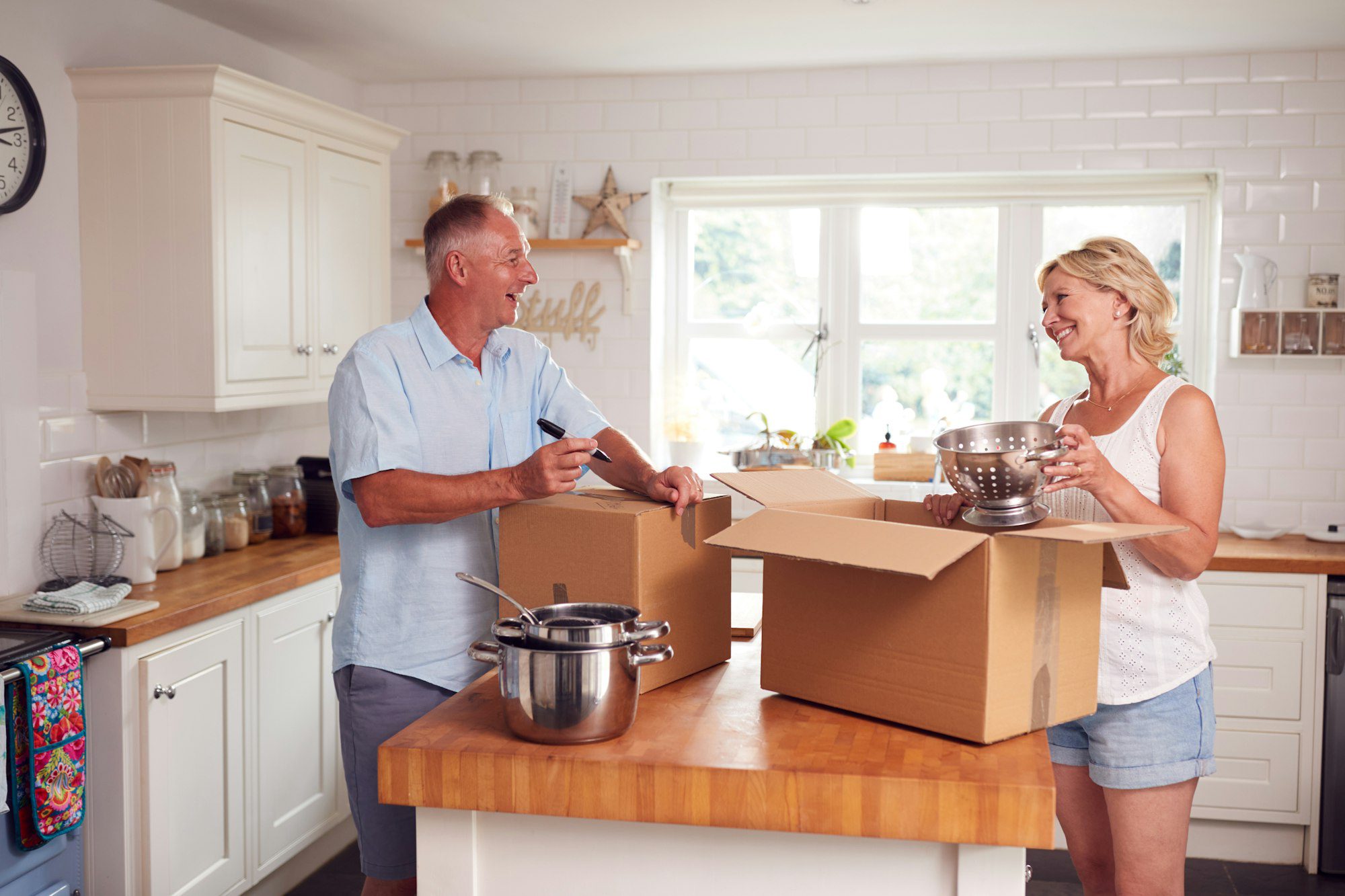 Senior Couple Downsizing In Retirement Packing And Labelling Boxes Ready For Move Into New Home