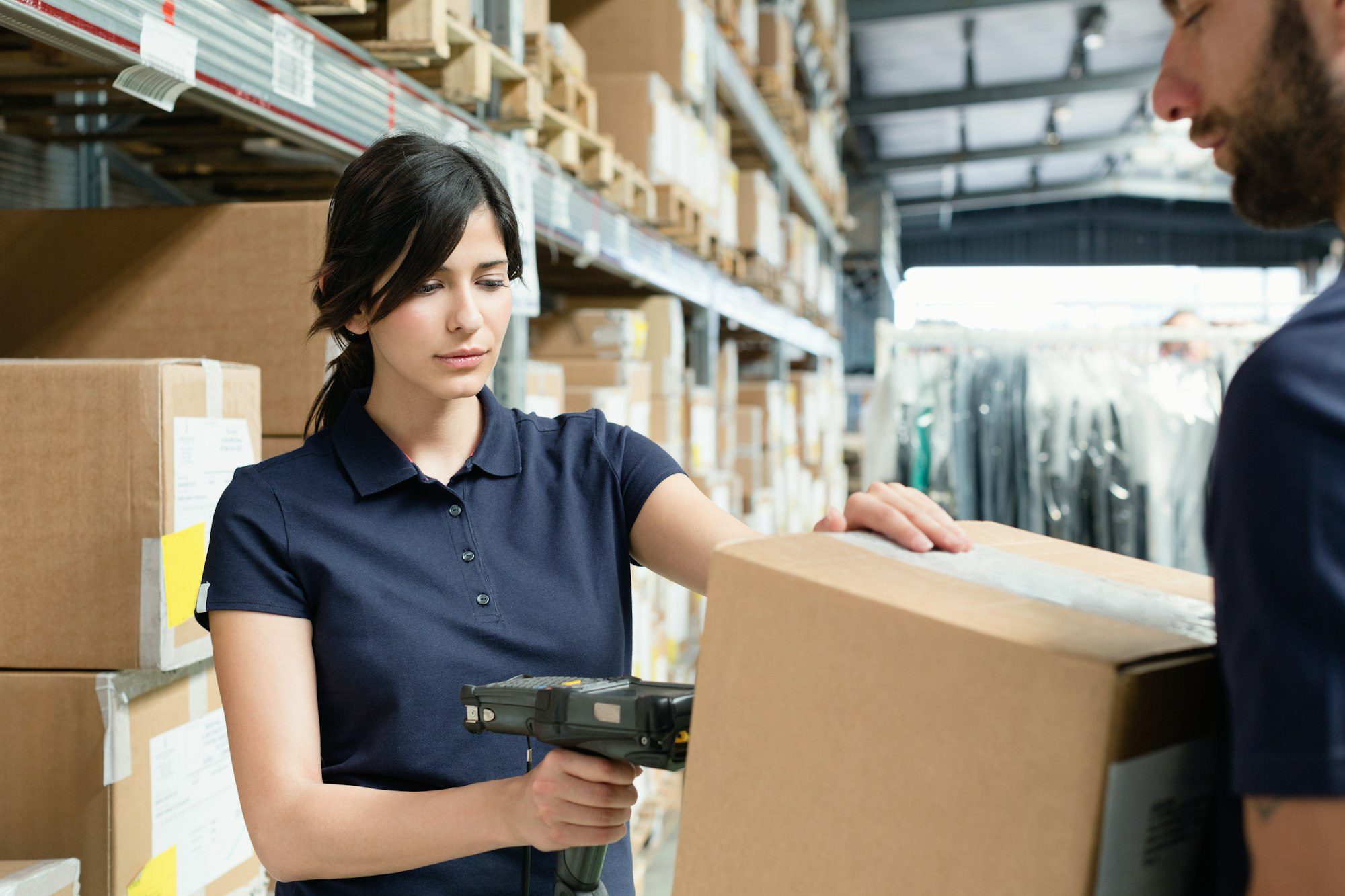 Warehouse workers using barcode scanner on box in a distribution warehouse