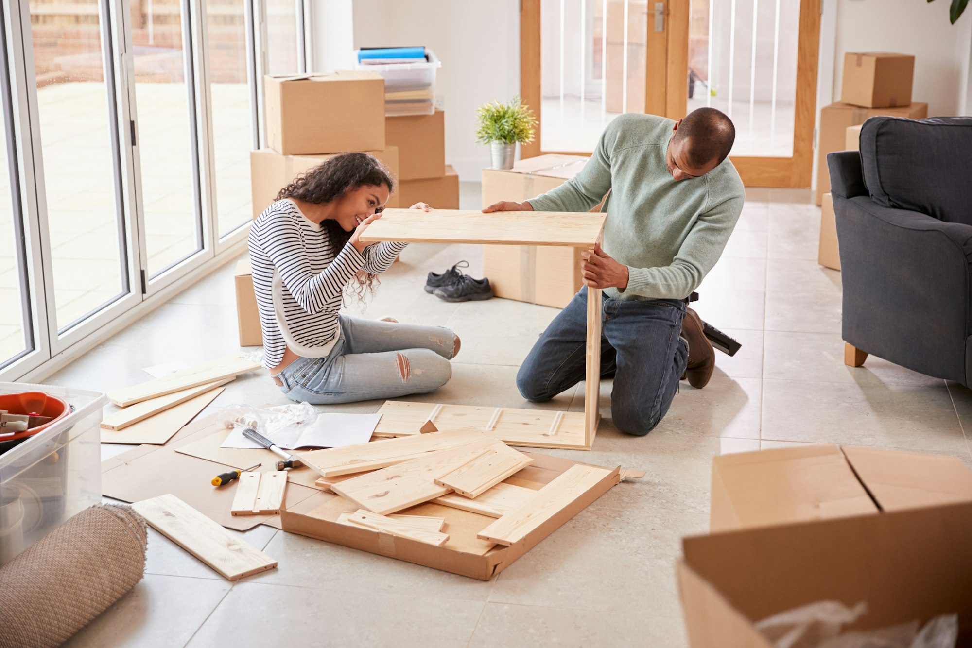 Couple In New Home On Moving Day Putting Together Self Assembly Furniture